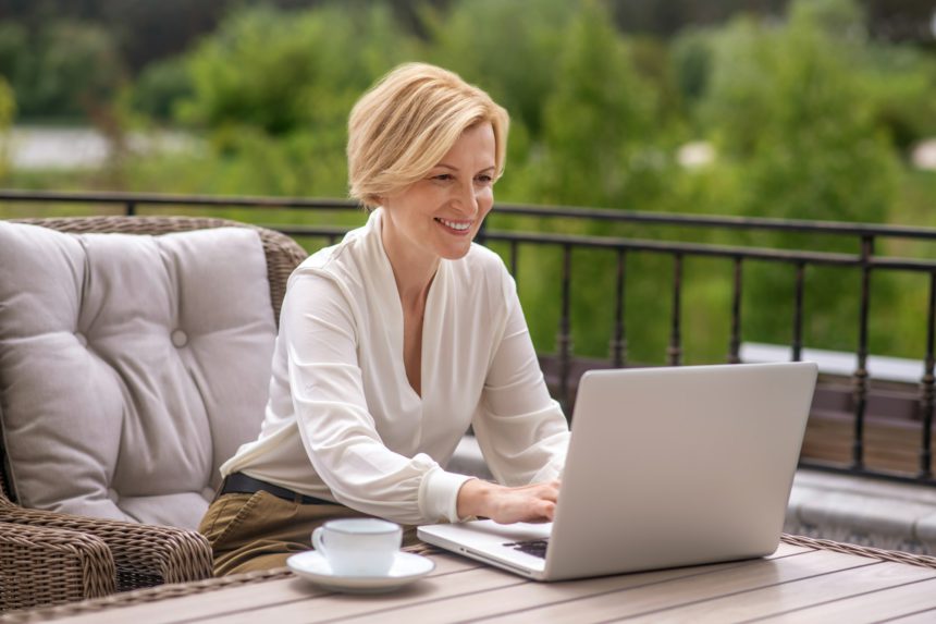 Joyful woman writing an email on the notebook computer